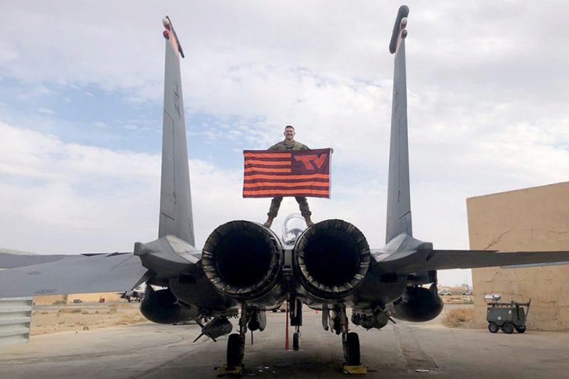 一个军团的校友站在飞机上举着买球app的旗帜.